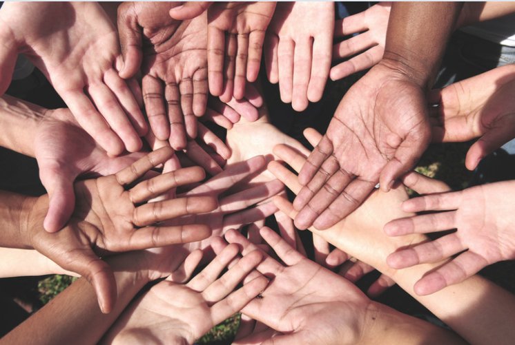 Diverse hands gathered in a circle with palms open, mutual community care