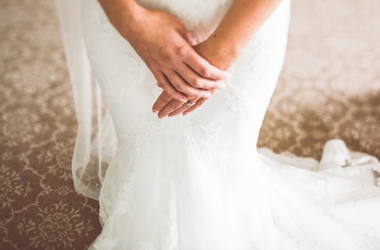 Bride in her wedding gown, hands gently folded, honored and beautiful