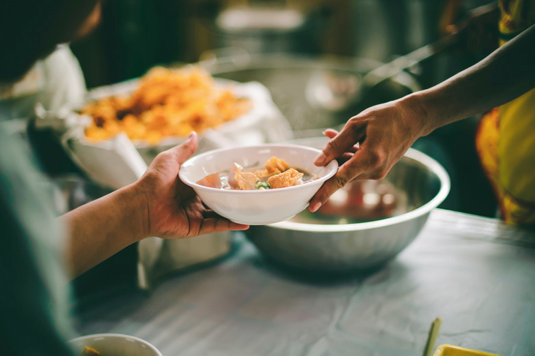 Hands sharing a bowl of food, reflecting ECO's feeding programs in Haiti