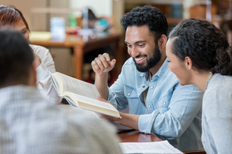 Friends gathered around a table, smiling as they read together